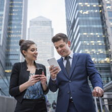 Businessman and businesswoman using mobile phone, Canary Wharf, London, UK