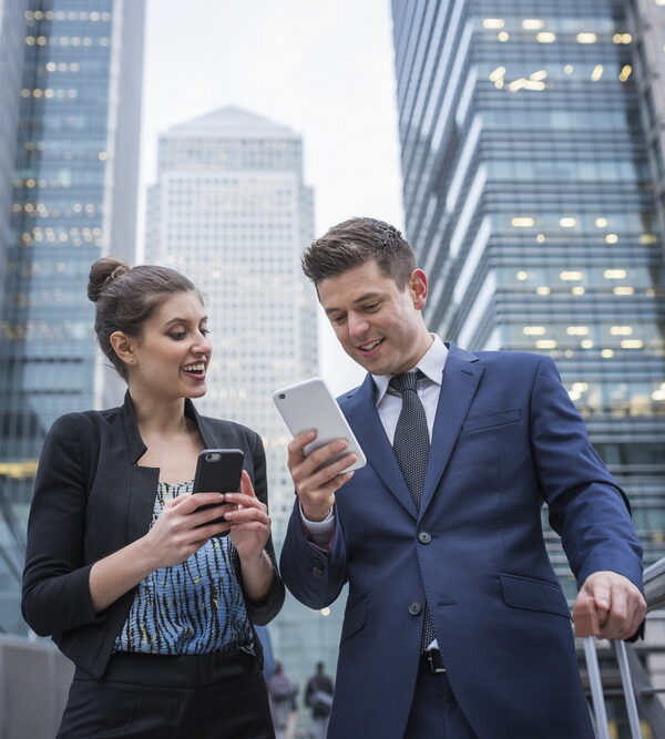 Businessman and businesswoman using mobile phone, Canary Wharf, London, UK