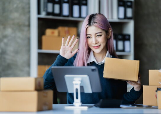 Asian fashion video blogger selling empty boxes online with smartphones.