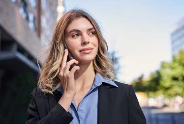 Close up portrait of smiling saleswoman, successful female manager having phone call, answer telephone and walking on street.