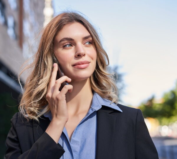 Close up portrait of smiling saleswoman, successful female manager having phone call, answer telephone and walking on street.