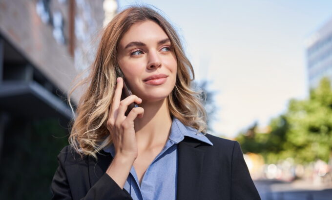 Close up portrait of smiling saleswoman, successful female manager having phone call, answer telephone and walking on street Close up portrait of smiling saleswoman, successful female manager having phone call, answer telephone and walking on street.